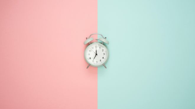 a clock illustration on a pink and green background