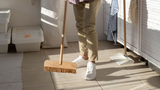 man holding a broom ready to sweep the floor