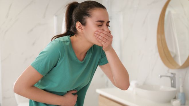 women holding her mouth to control vomiting