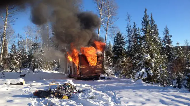 A person dreaming of escaping a house fire from a small house around snow