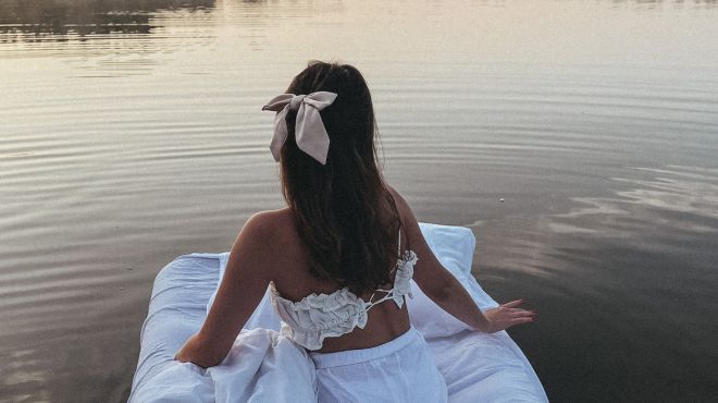 girl dream about a she is on a floating bed on a lake