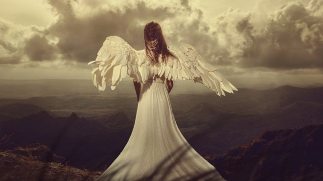 man dreaming of an angel with white wings on a mountain