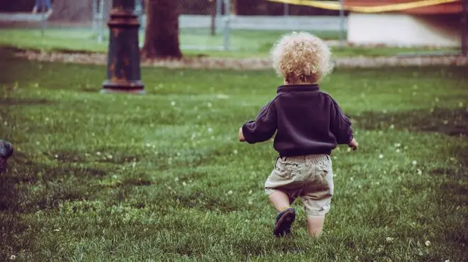 little son walking down a lawn garden